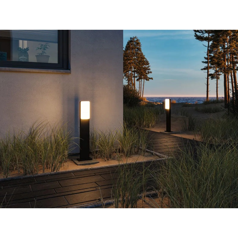 Paulmann outdoor 230V Bonnie LED bollard light with a sleek black finish, illuminating a garden pathway.