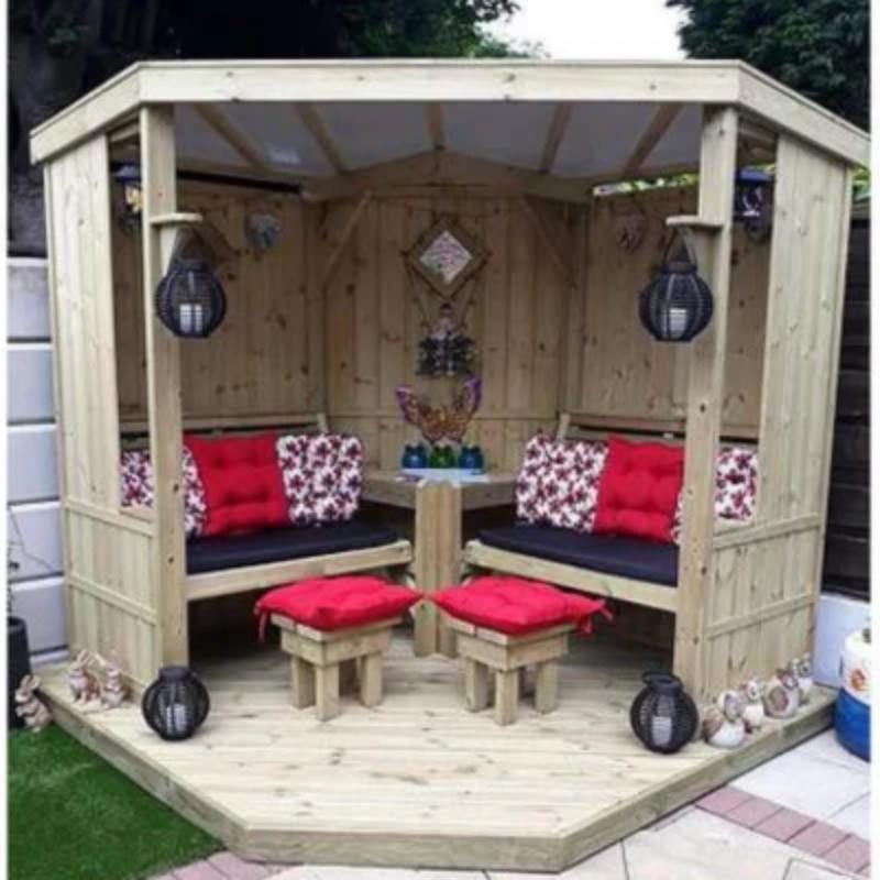 Churnet Valley wooden garden room with decking, featuring red cushions and lanterns, ideal for outdoor relaxation.