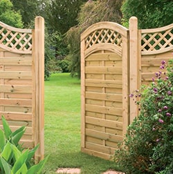 Natural wood garden gate with trellis design, set in a green landscape.
