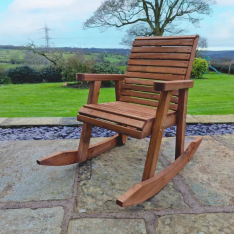 Churnet Valley wooden rocking chair with slatted design, set on a stone patio in a garden landscape.